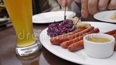 一个<strong>盘子</strong>里放着德国香肠和卷心菜，旁边放着一杯啤酒，客户把<strong>盘子</strong>放在他的<strong>盘子</strong>里。 关门